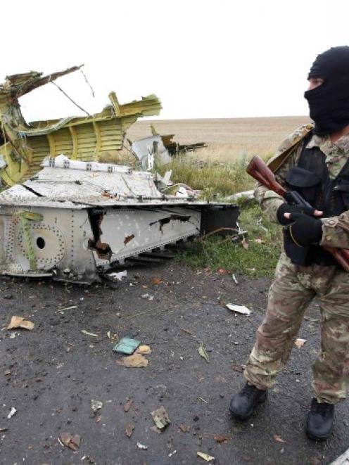 A pro-Russian separatist stands at the crash site of Malaysia Airlines flight MH17, near the...