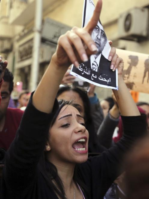 A protester chants anti-government slogans while holding a poster of Egyptian Interior Minister...