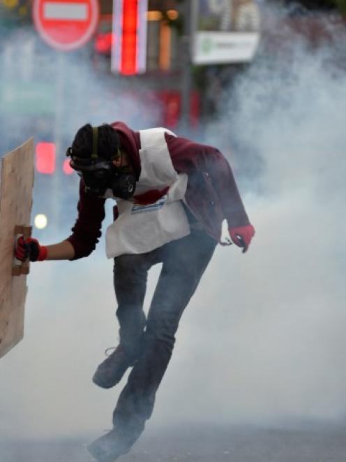 A protester runs away from tear gas fired by riot police during a demonstration in Ankara blaming...