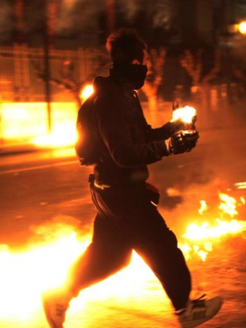 A protester runs with a petrol bomb towards riot police guarding the parliament in Athens'...