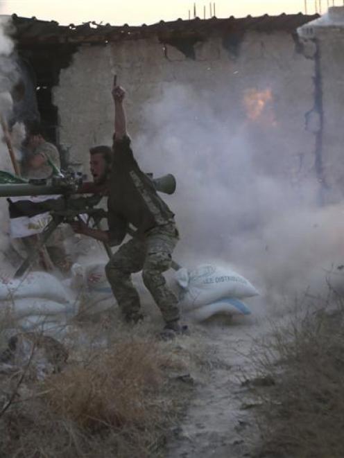 A rebel fighter gestures as he fires his weapon during clashes with forces loyal to Syria's...