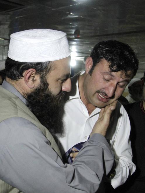 A relative is comforted while mourning the death of Samiullah Afridi, who was killed by...
