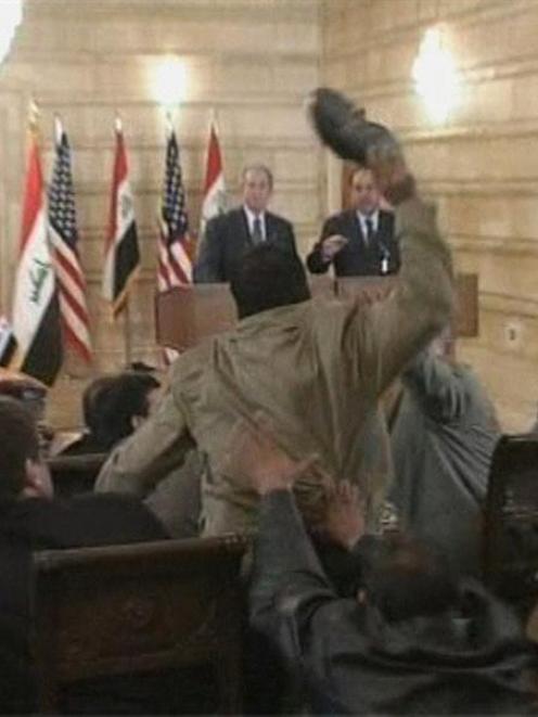 A reporter for Al-Baghdadiya television throws a shoe at President George W. Bush during a new...