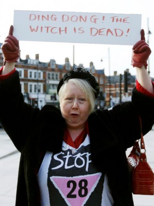 A reveller in Brixton, south London, holds a sign to celebrate the death of Britain's former...