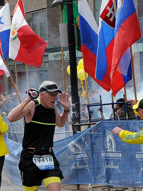 A runner and race officials react to an explosion during the Boston Marathon in Boston,...