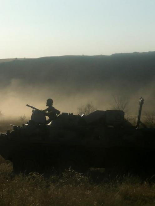A Russian serviceman rides atop an armoured personnel carrier through a field outside Kamensk...