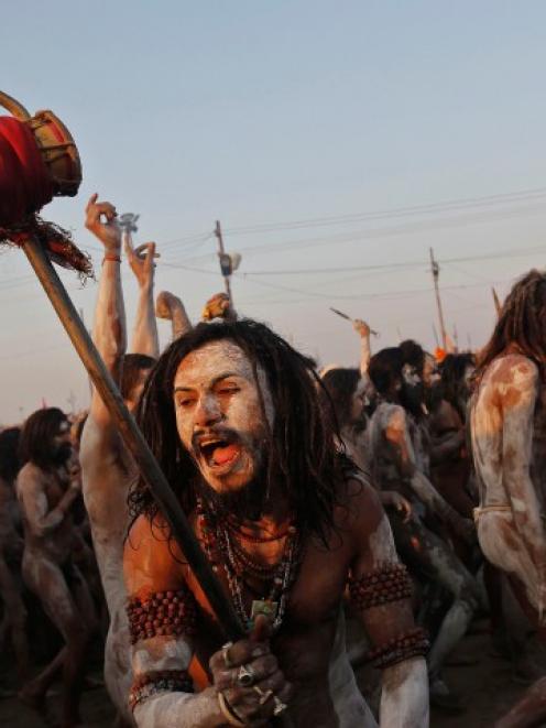 A sadhu, or Hindu holy man, shouts while holding a 'trishul' (trident-shaped weapon} after taking...