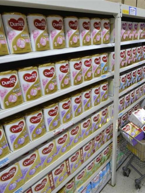 A sales assistant taking down milk powder products which were recalled by Fonterra last year....
