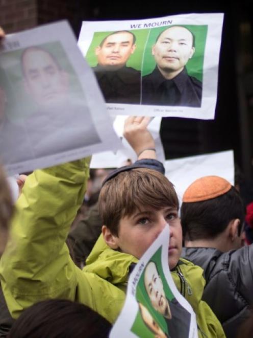 A schoolboy holds images of slain New York Police officers Wenjian Liu and Rafael Ramos, as he...