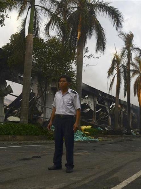 A security guard stands near a damaged Chinese-owned shoe factory in Vietnam's southern Binh...