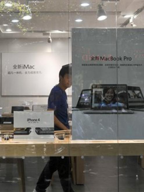 A shopkeeper dressed as an Apple store employee looks out from a window of a shop masquerading as...