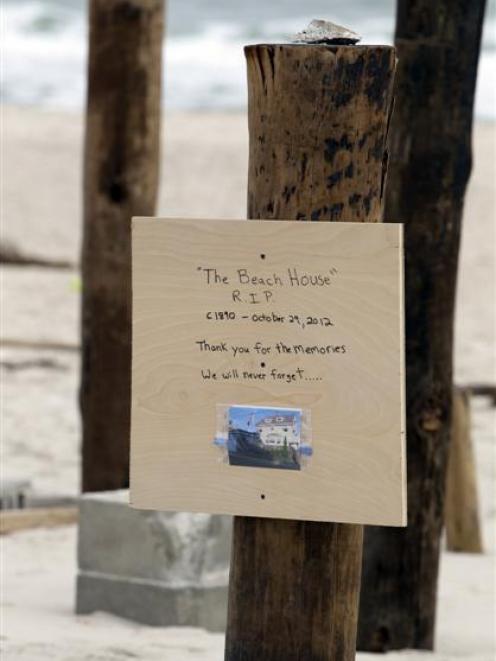 A sign with a photo nailed to one of several pilings, all that remains of a house that once stood...