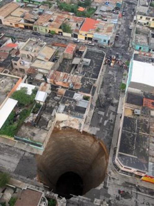 A sinkhole covers a street intersection in downtown Guatemala City. A day earlier authorities...