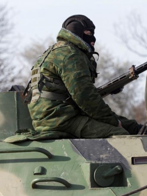 A soldier, believed to be Russian, rides on a military armoured personnel carrier on a road near...