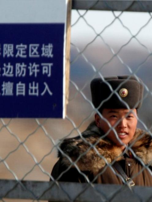 A soldier stands guard on Hwanggumpyong Island in the middle of the Yalu River, near the North...