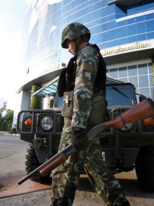 A soldier walks in front of the National Broadcasting Services of Thailand television station in...