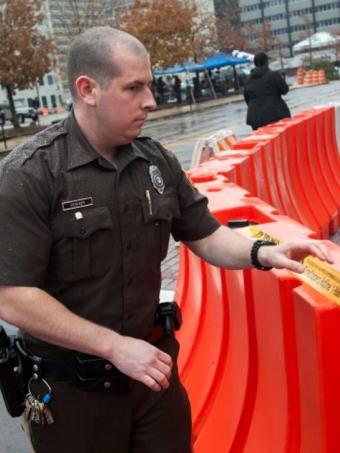 A St. Louis County Security Officer places police tape along a barricade outside Buzz Westfall...