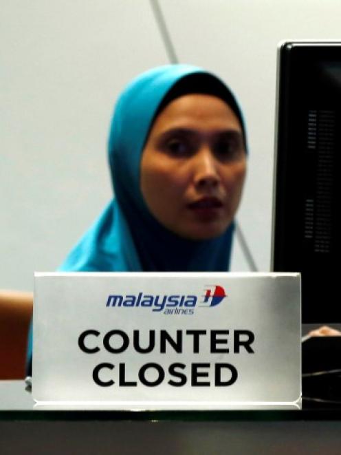 A staff member sits behind a closed Malaysia Airlines desk at Kuala Lumpur International Airport...
