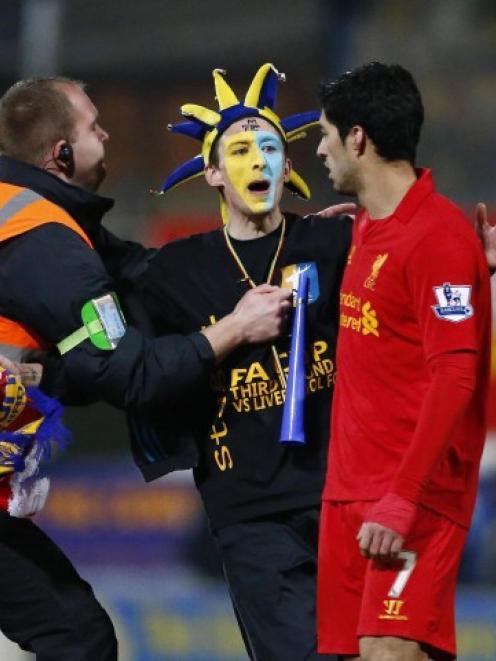 A steward prevents a Mansfield Town supporter from reaching Liverpool's Luis Suarez (R) during...