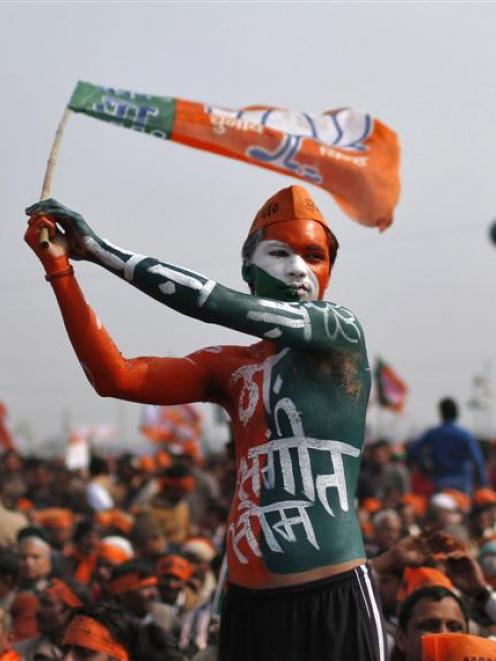 A supporter  of BJP waves the party's flag during a rally being addressed by Mr Modi at Meerut in...