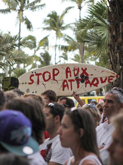 A surfboard with the message "Stop the attacks" is seen during a demonstration attended by 300...