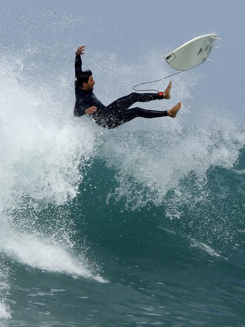 A surfer falls off his board as he rides a wave amid large ocean swells in Cardiff, California....