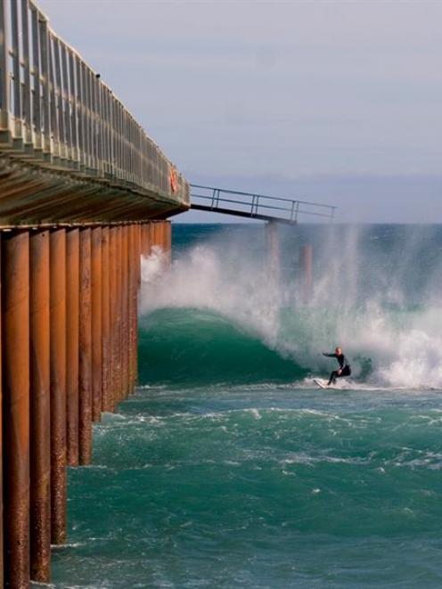 A surfer takes advantage of the conditions near the Tahuna sewage outfall construction jetty...