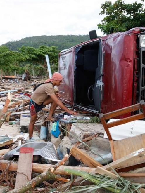 A survivor sorts through debris after a tsunami struck the South East coast villages of Samoa....
