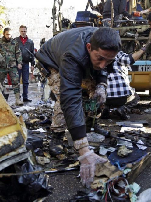A Syrian soldier gathers evidence after an explosion occurred on a bus in central Damascus. Photo...