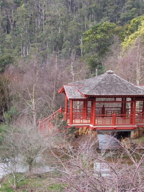 A tea house is surrounded by Japanese rhododendrons, cherries and magnolias, with a backdrop of...