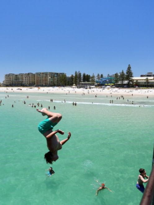 A teengager jumps off the jetty at Glenelg Beach in Adelaide. Five straight days of temperatures...