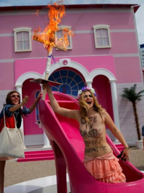 A topless activist from women's rights group Femen protests outside a 'Barbie Dreamhouse' of...