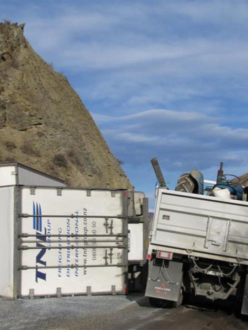A truck squeezes around the crashed trailer on State Highway 8 after yesterday's crash. Photo by...