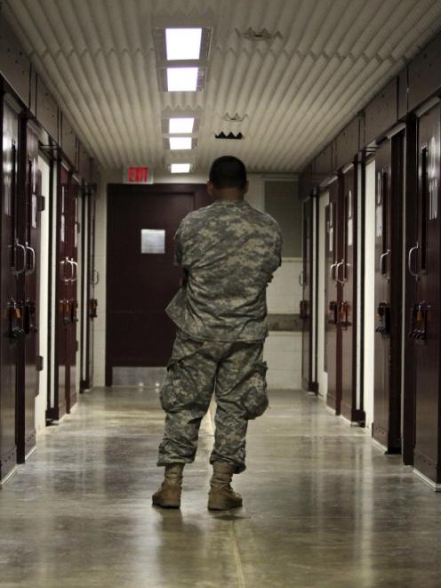 A U.S. military guard stands in a cell block at the Camp 5 detention facility at Guantanamo Bay....