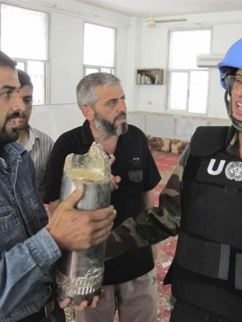 A United Nations observer is shown a shell last week after a bombardment of Homs city. Photo by...