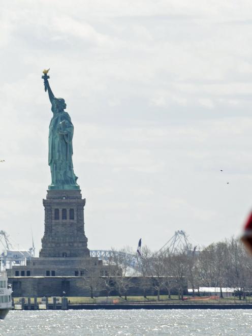 A United States flag flutters in the wind off of a Statue of Liberty Island ferry boat in lower...