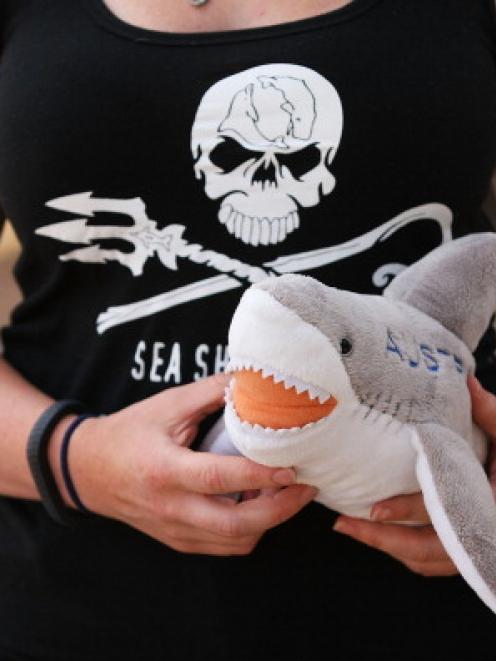A woman holds a shark plush toy in protest against the catching and killing of sharks in Western...