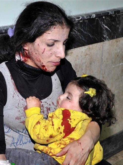 A woman hugs her daughter who was injured in an explosion in Hai al-Wuroud, as they wait in a...