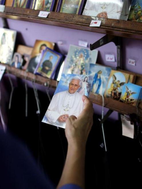 A woman looks at a postcard with a photograph of Pope Benedict XVI inside a church store in...