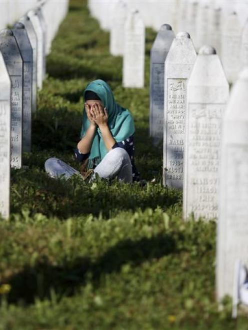 A woman mourns among graves in Memorial Centre Potocari, near Srebrenica, on Saturday as...