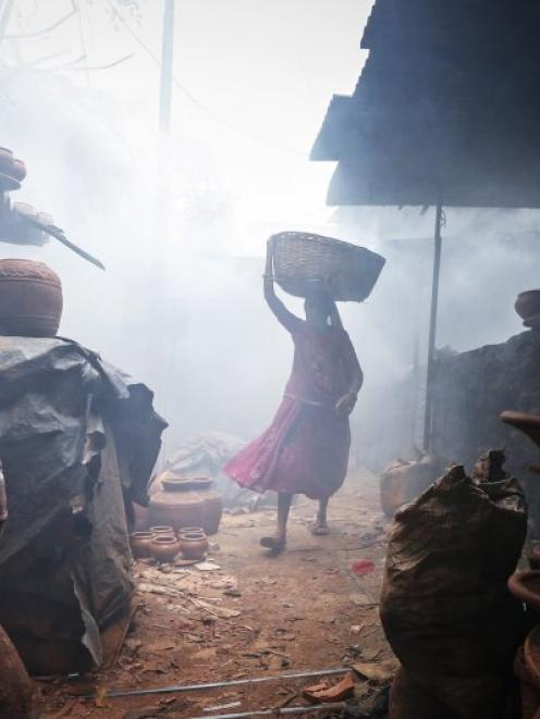 A woman potter carries earthen pots through traditional pottery kilns in Dharavi, one of Asia's...