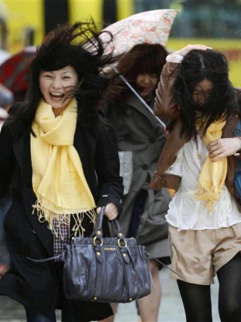 A woman reacts to a gust of wind outside Tokyo train station as a rainstorm batters Japan. (AP...