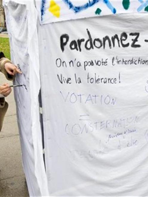 A woman writes slogans on a symbolic minaret erected to protest against the results of a vote in...