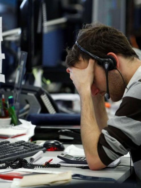A worker on IG Index's trading floor in London holds his head in his hands as markets tumble...