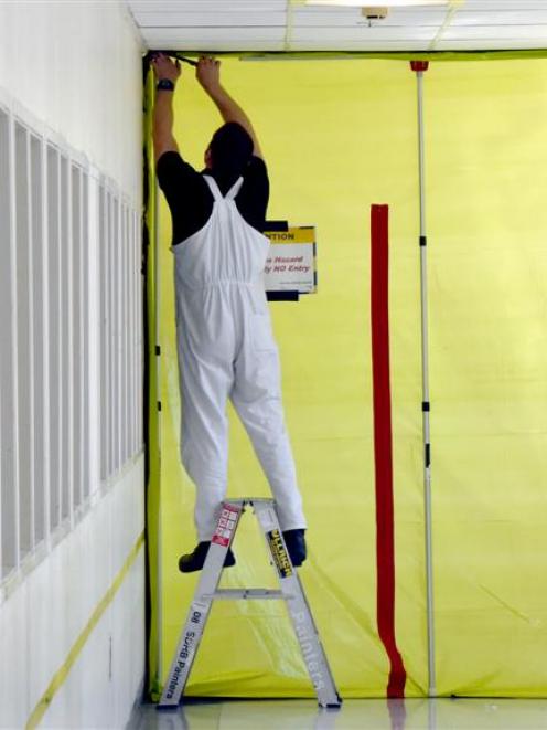 A worker secures screening material to the entrance of the ultrasound suite.