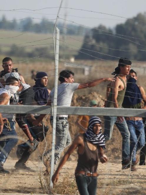 A wounded Palestinian protester is carried away after he was shot by Israeli troops near the...