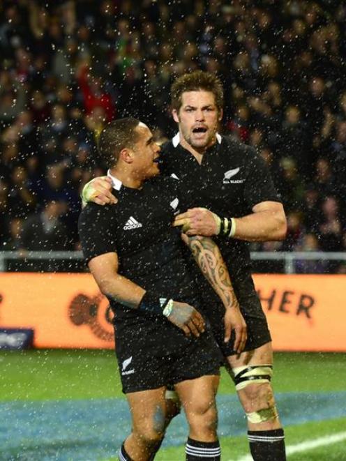 Aaron Smith (left) is congratulated by All Black captain Richie McCaw and gets sprayed by beer...