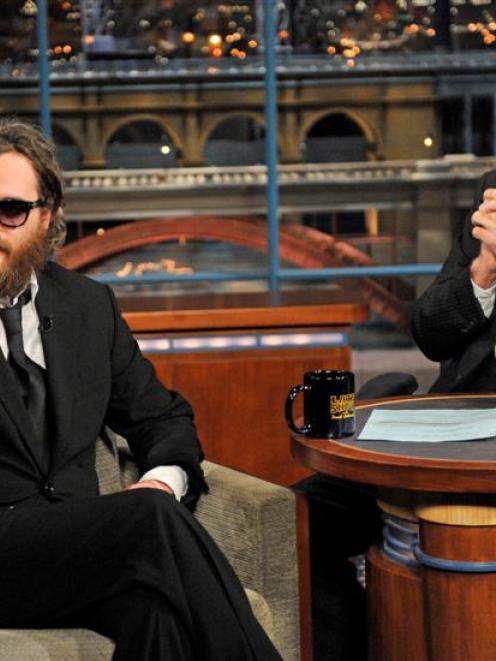 Actor Joaquin Phoenix, left, waves to the audience from the set of the 'The Late Show with David...