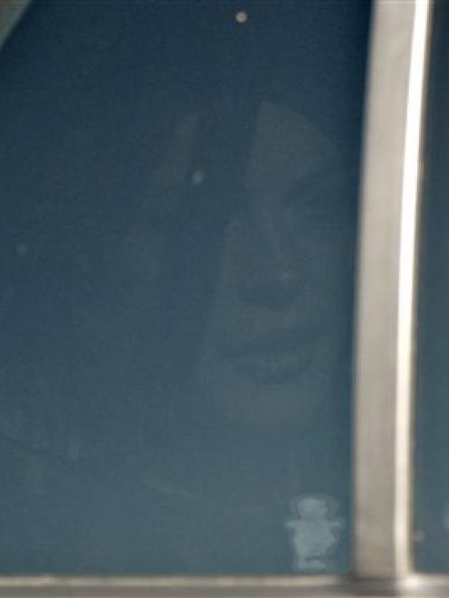 Actress Lindsay Lohan is seen through a tinted car window inside an unmarked police car as she...