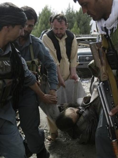 Afghan police men carry the body of suicide bomber wrapped in a carpet inside governor's compound...